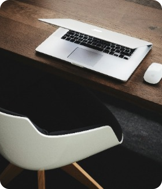 Half CLosed MacBook on a Desk with a Chair